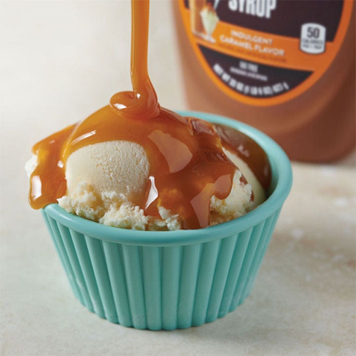 Hersheys caramel syrup pouring on top of ice cream in a bowl